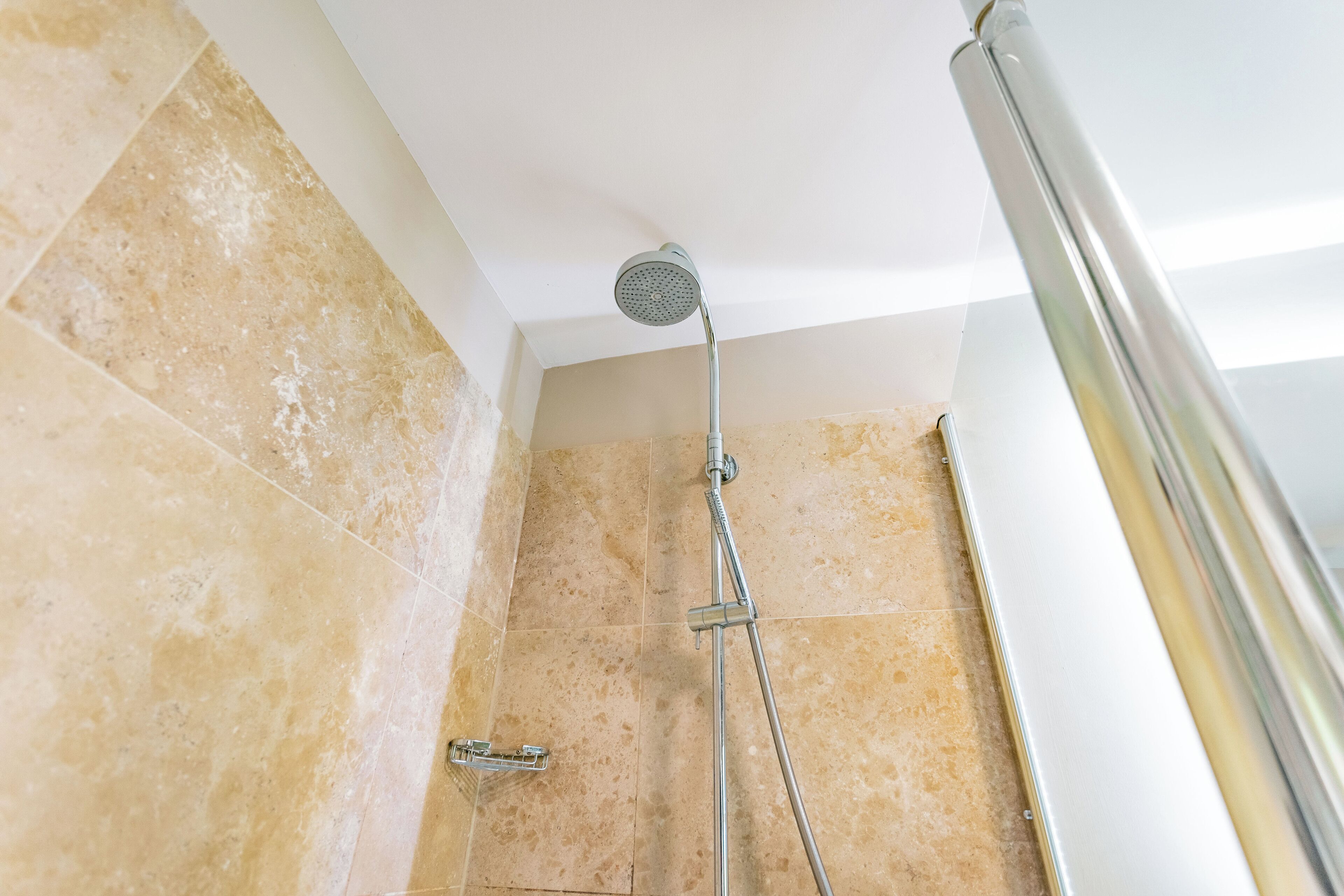 A shower with a handheld showerhead and a wall-mounted faucet.