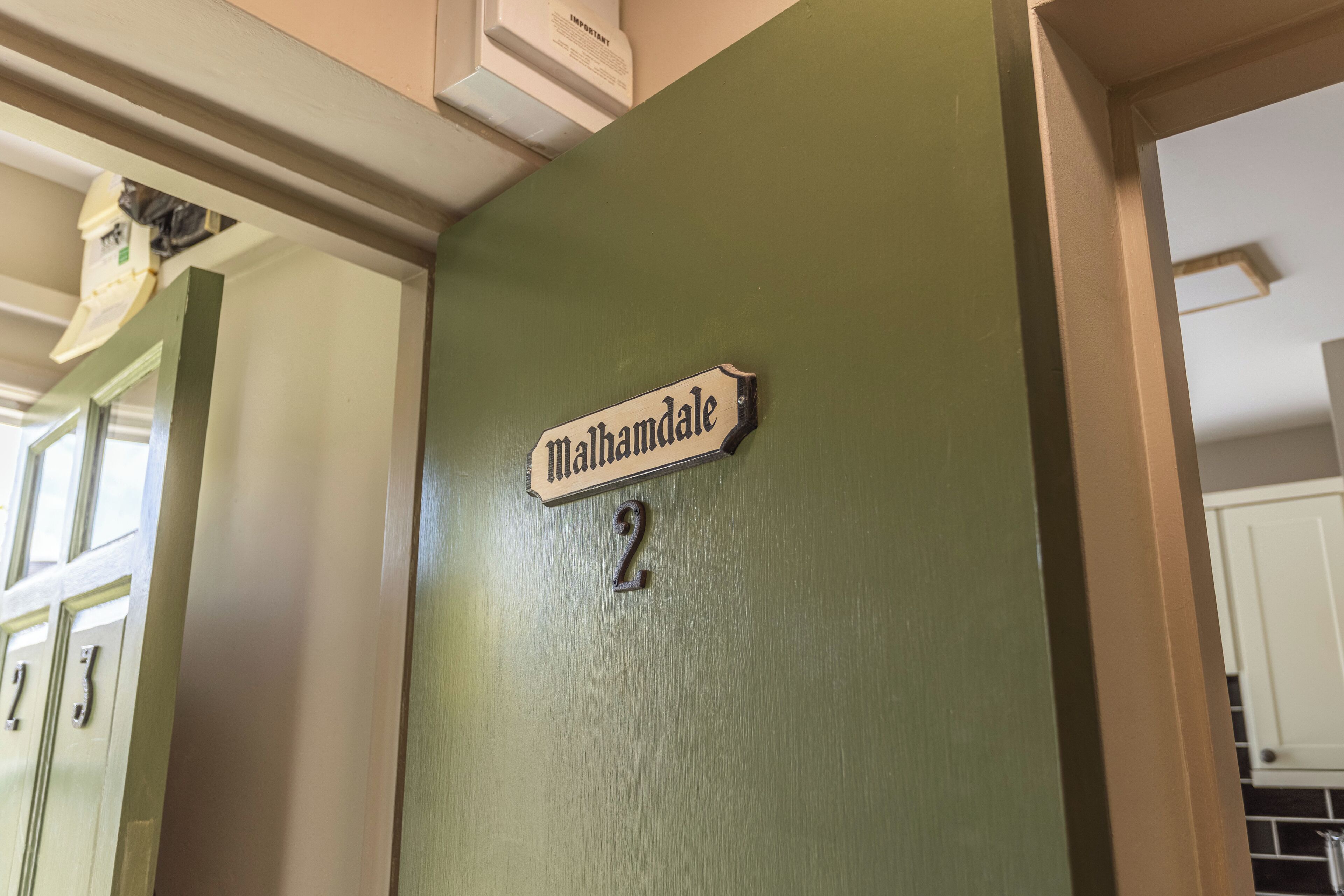 A room with a green wall, a door labeled "Walthamdale 2", and a white door with a number "2" above it.