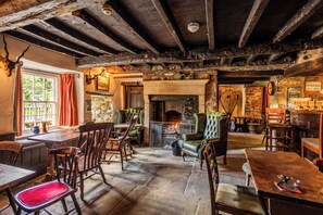 Un pub rústico con vigas de madera a la vista, una chimenea y muebles de madera tradicionales.