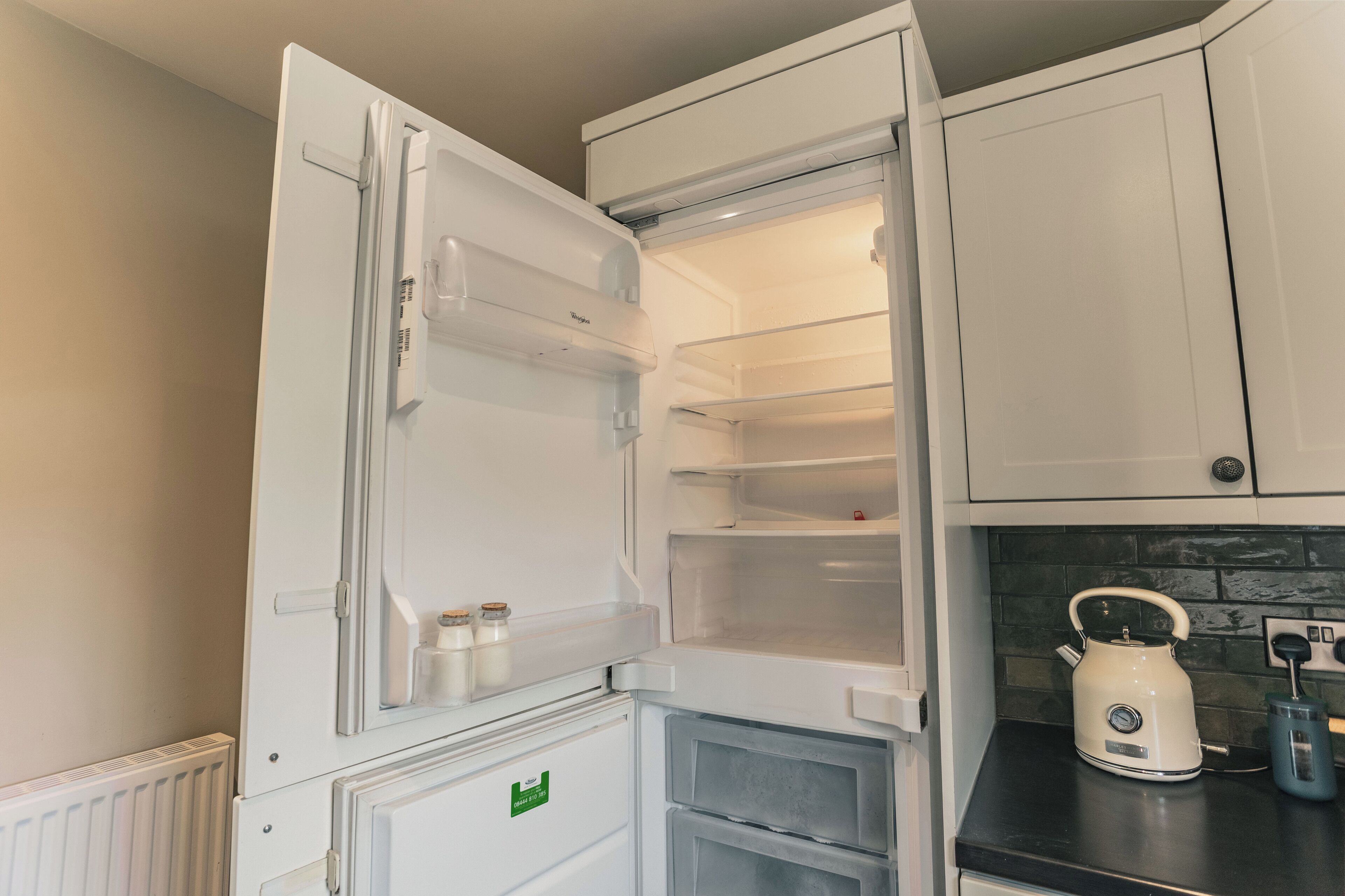 Een keuken met een witte koelkast, een waterkoker en een broodrooster op het aanrecht.