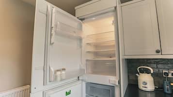 Een keuken met een witte koelkast, een waterkoker en een broodrooster op het aanrecht.