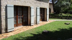 A stone building with two doors, each with shutters, and a paved pathway leading to the entrance. - Gite les Lavandes, 4 Personnes (VALROS)