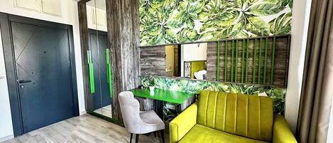 A modern room with a green desk, a yellow sofa, and a large mirror.
