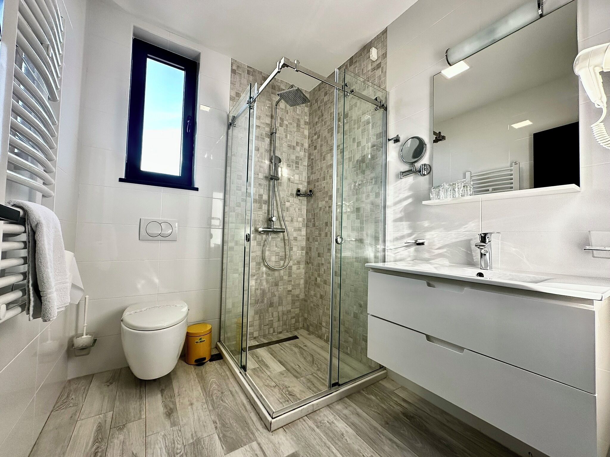 A modern bathroom with a glass-enclosed shower, a toilet, and a vanity with a mirror.