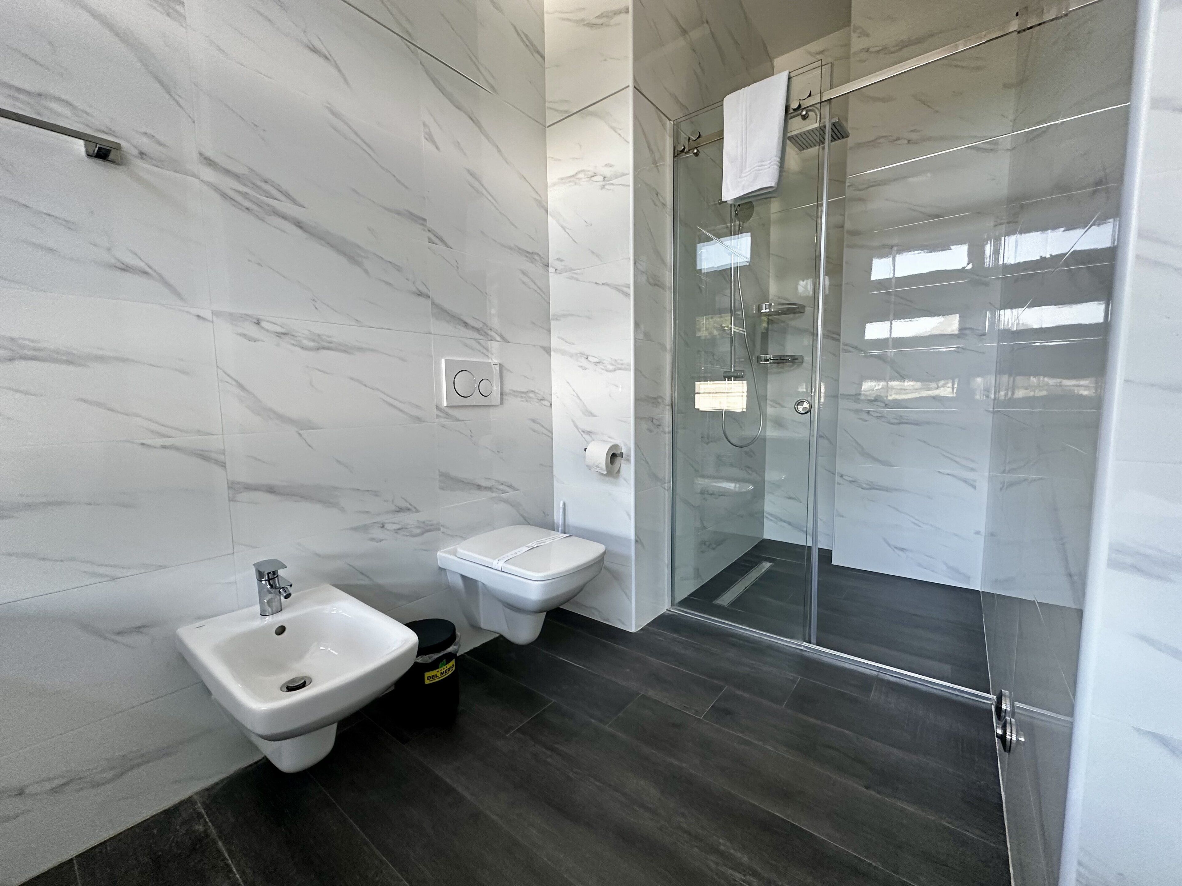 A modern bathroom with a bidet, toilet, and glass-enclosed shower.