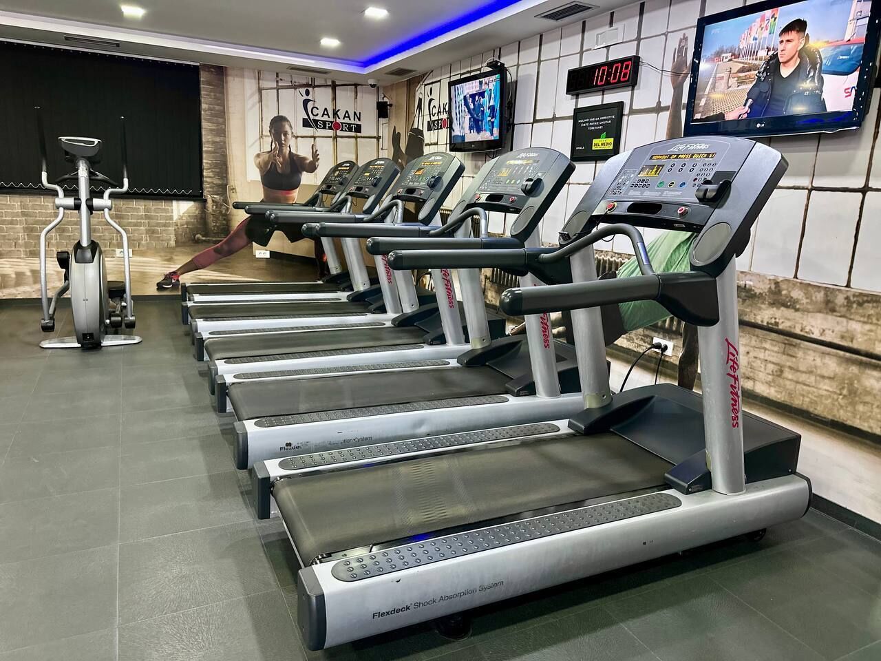 A gym with multiple treadmills, a stationary bike, and a wall-mounted TV.
