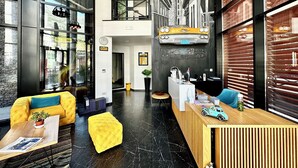 A modern lobby with a reception desk, seating area, and a staircase leading to an upper level. - Hotel Del Medio (Sutomore)