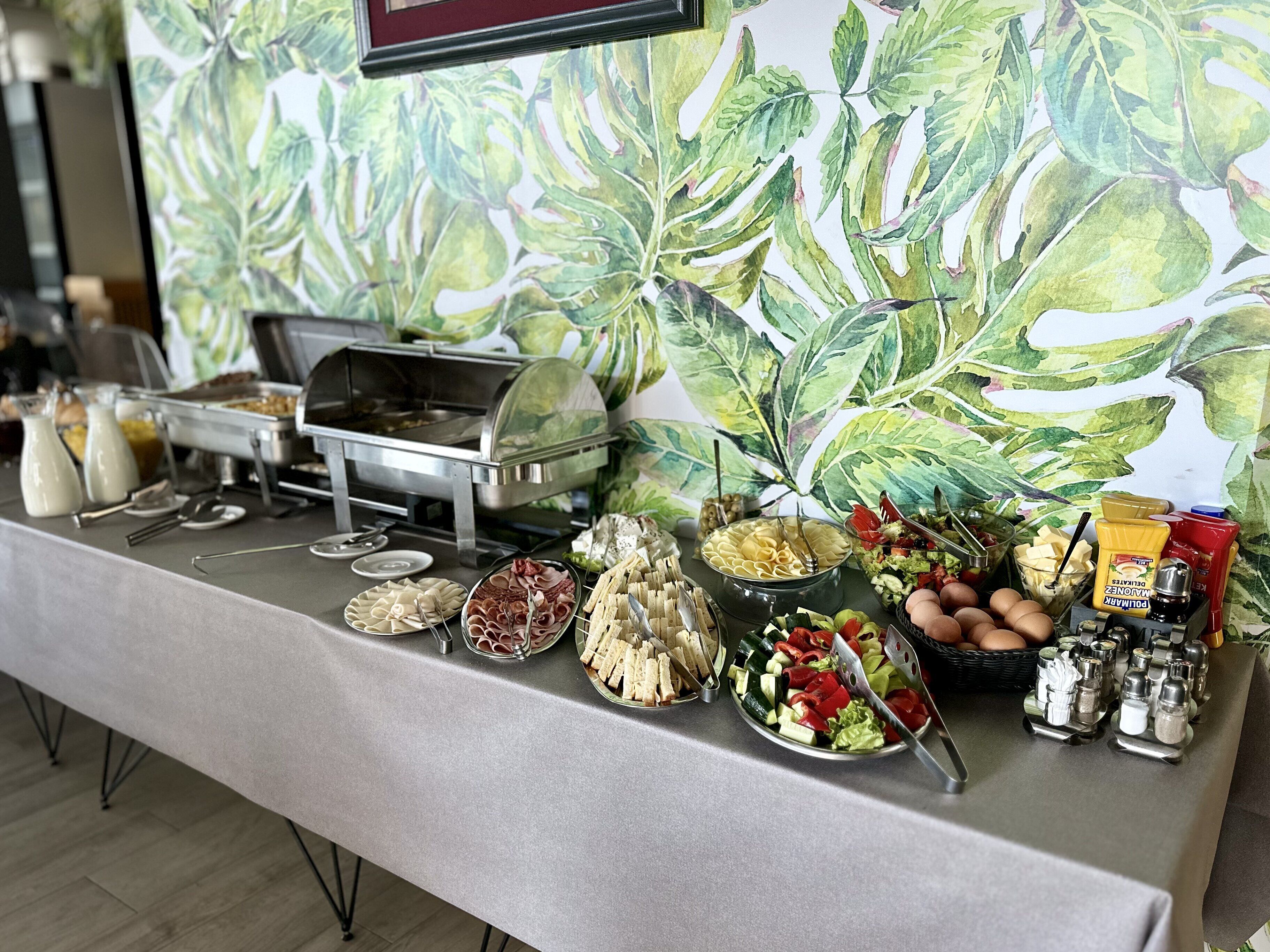 A buffet table with various food items and condiments.