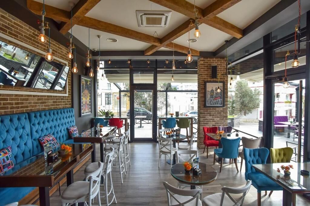 A modern cafe with exposed brick walls, wooden beams, and a mix of bar and table seating.