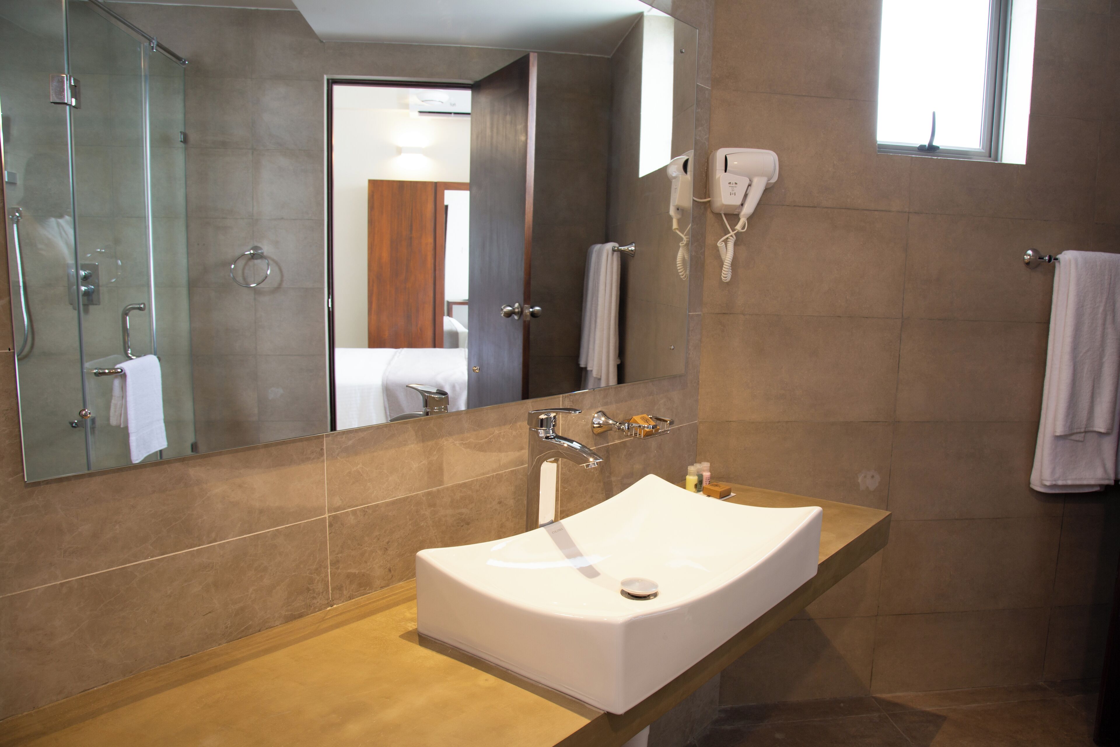 A modern bathroom with a large mirror, a white sink, and a handheld showerhead.