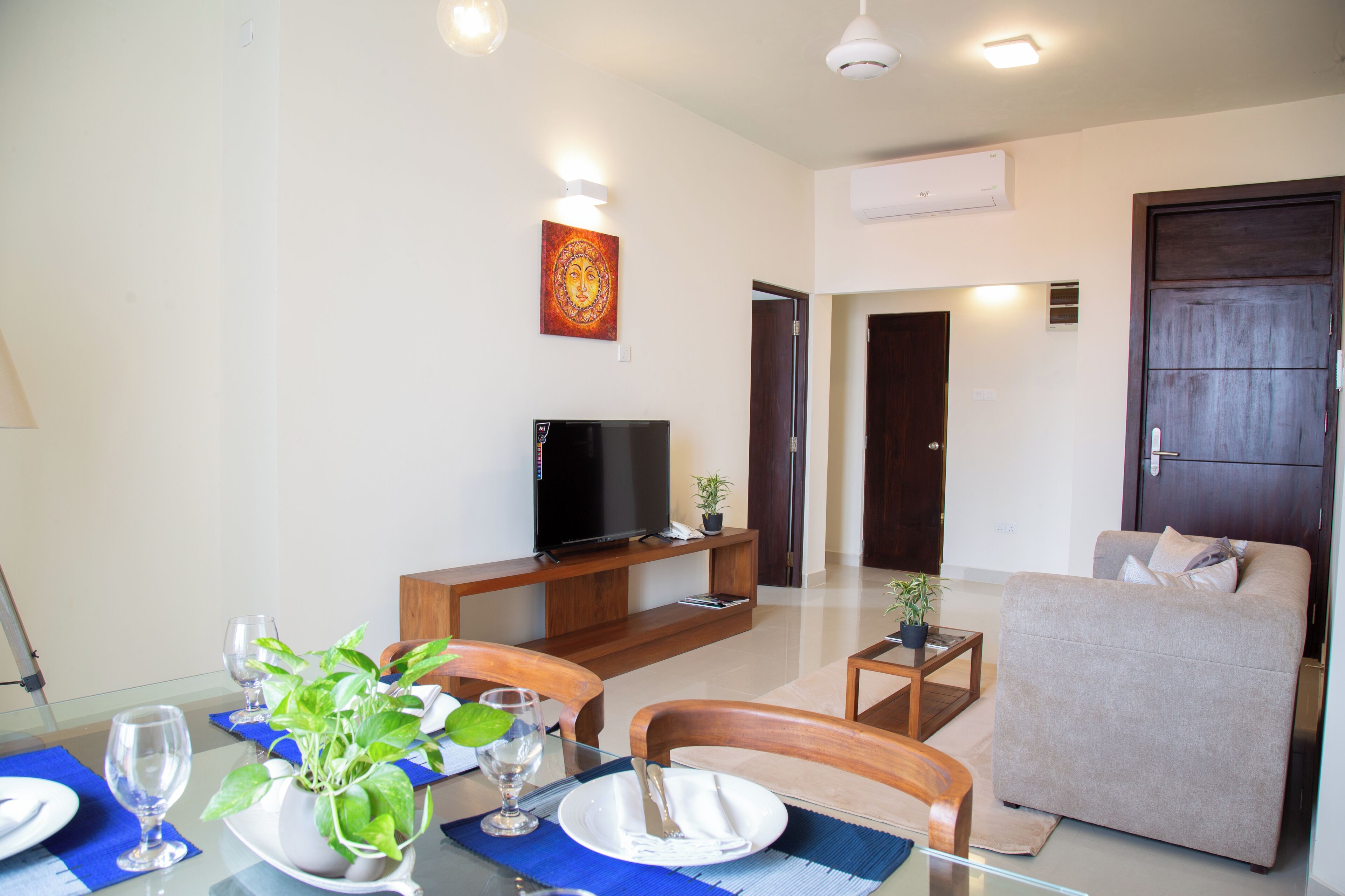 A modern living room with a sofa, a TV, and a dining table set for two.