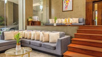 A modern living area with a grey sofa, a glass coffee table, and a wooden staircase.