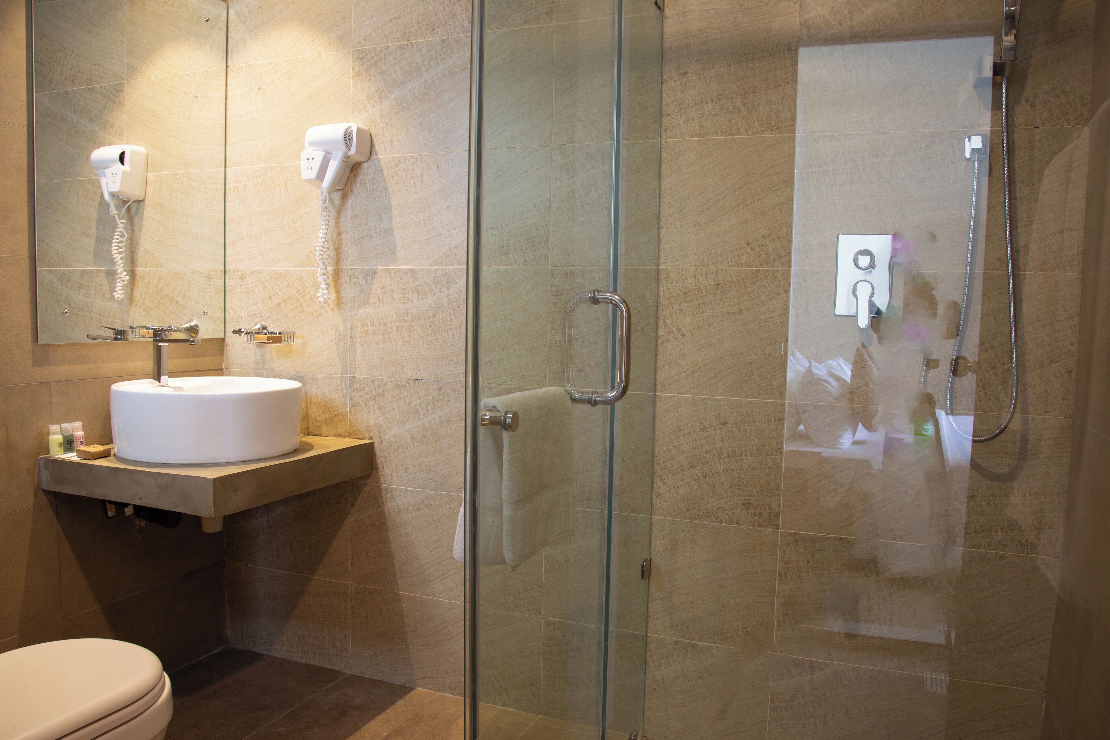Un bany amb dutxa tancada per vidre, un lavabo amb mirall i un vàter.