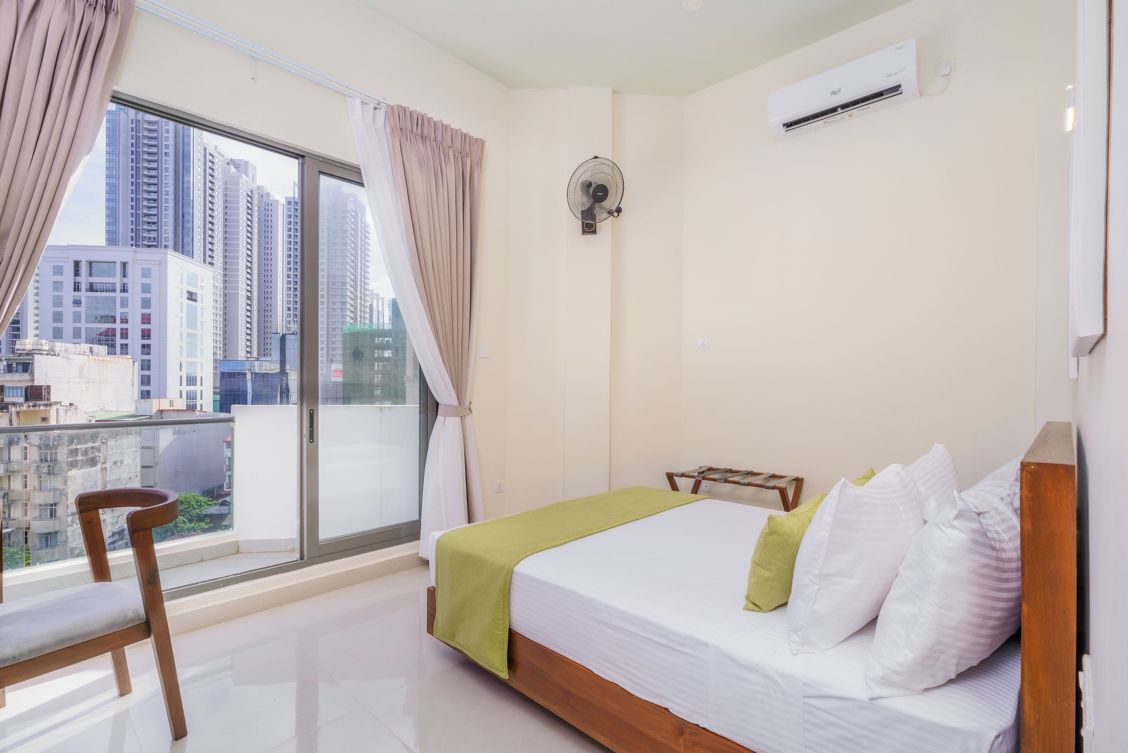 Een slaapkamer met een bed, een stoel, een ventilator en een airconditioning.