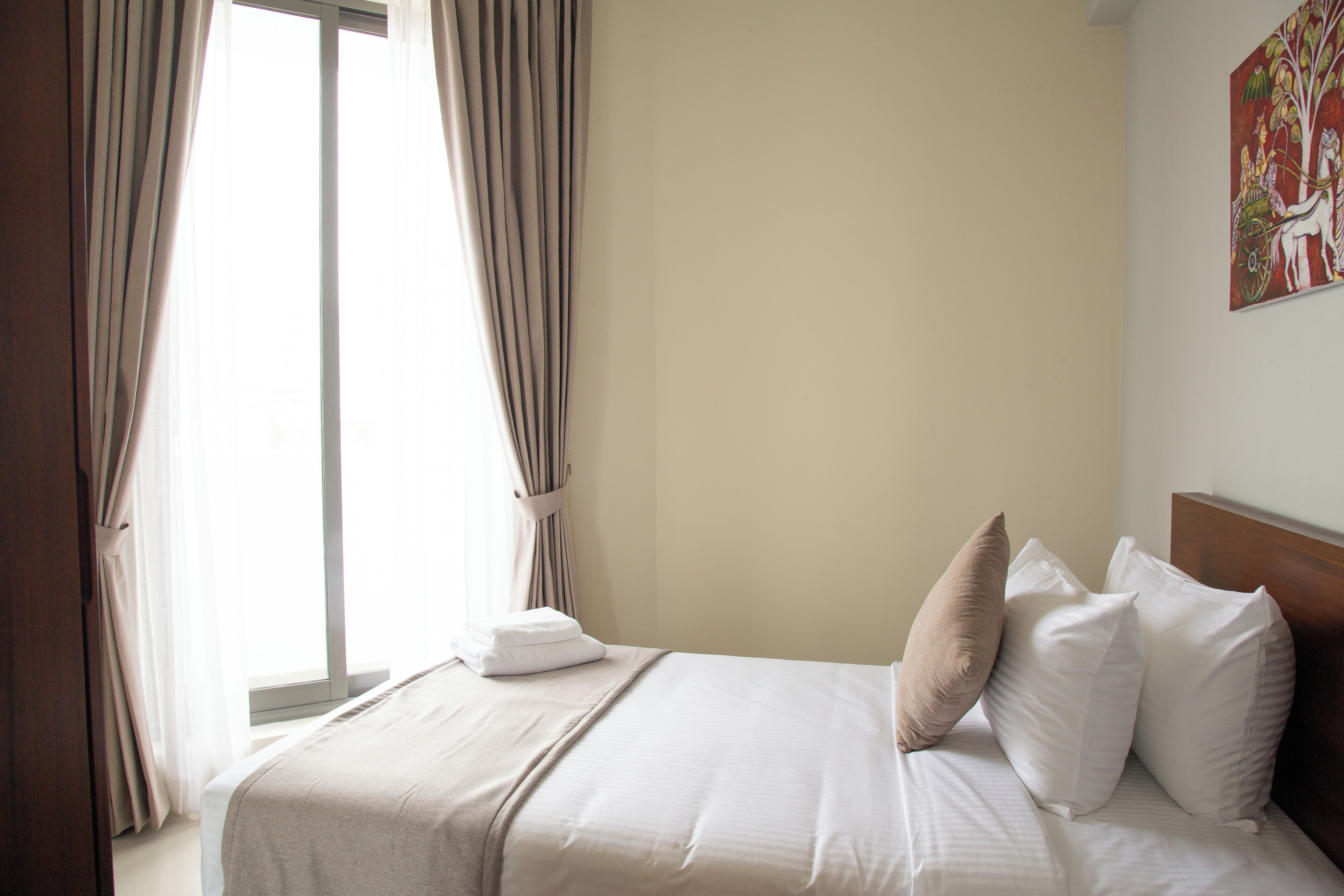 Une chambre d’hôtel avec un grand lit, une fenêtre avec des rideaux et un tableau au mur.