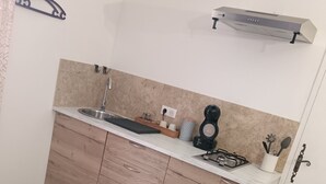 A compact kitchen with a sink, wooden cabinets, a microwave, and a small countertop. - Studio Neuf à Maillane (Maillane)