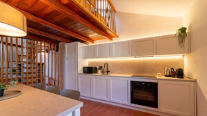 Una cocina moderna con armarios blancos, techo de madera y horno empotrado.