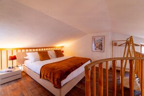 A bedroom with a wooden bed, white walls, and a wooden floor. - Appartamento La Chiocciola by Wonderful Italy (Bellagio)