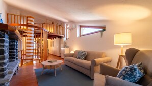 Una sala de estar acogedora con chimenea, una escalera espiral de madera y un espacio de descanso confortable.