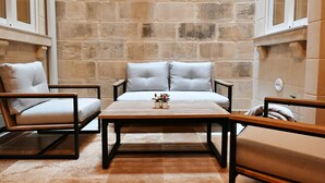 A room with a stone wall, two chairs, a sofa, and a table. - A Unique and Charming Farmhouse with Heated Pool. (L-Gnasri)