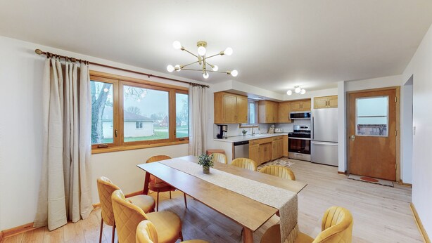 Eine moderne Küche mit Holzausbau, einem Edelstahlkühlschrank und einem Essbereich mit einem Holztisch und gelben Stühlen.
