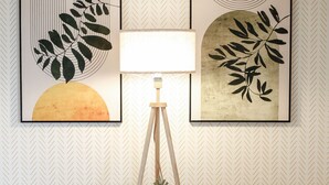 Ein Zimmer mit zwei gelben Sesseln, einer Stehlampe und zwei gerahmten Kunstwerken an der Wand.