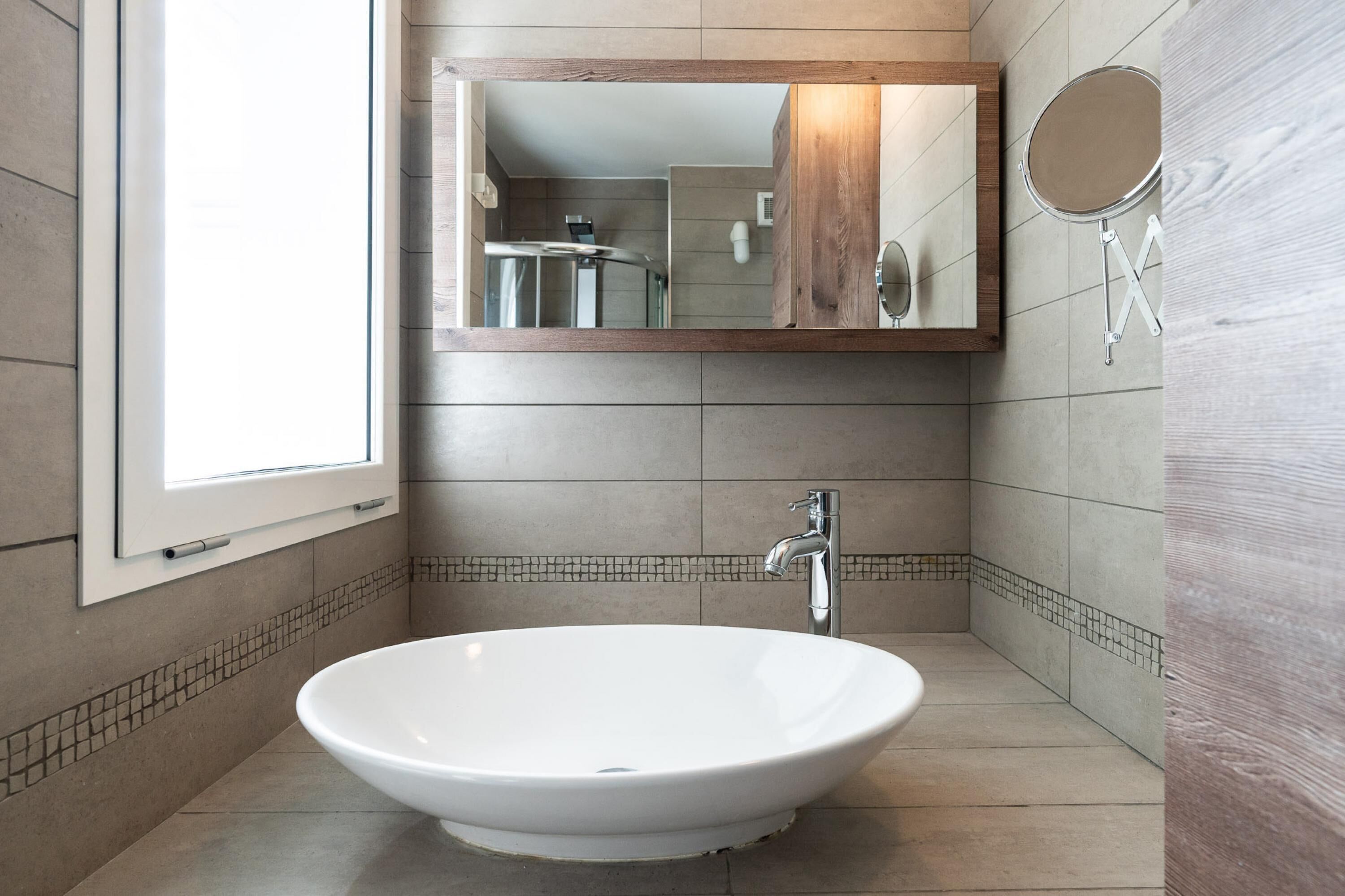 Un baño con un lavamanos ovalado grande, un espejo y una ventana.