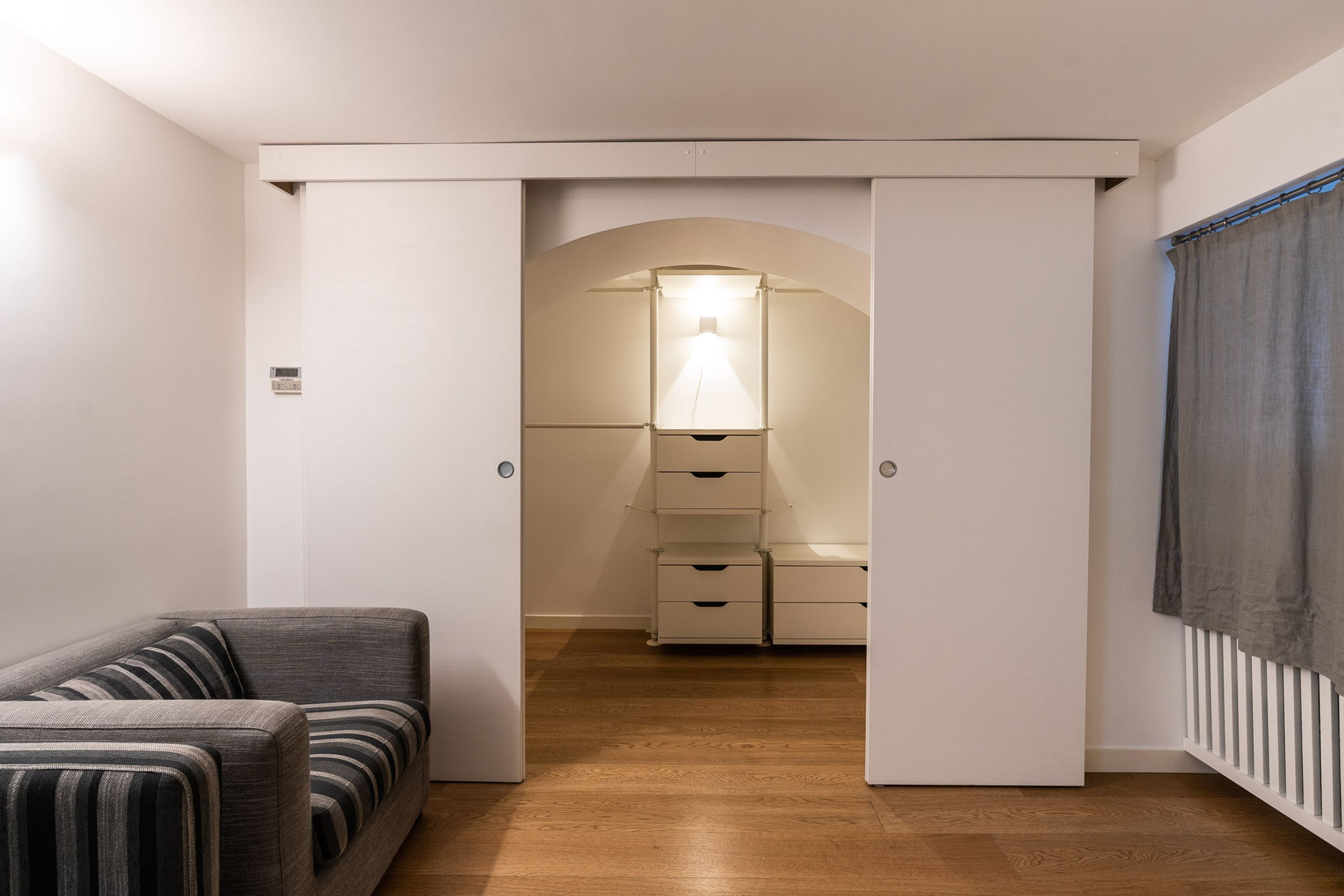 Ett modernt rum med en soffa, en garderob och en lampa.
