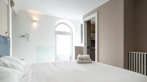 A hotel room with a large bed, a wardrobe, a bathroom, and a view of the outside.
