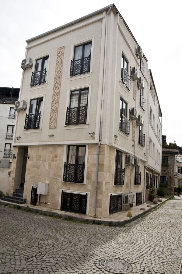 A multi-story building with balconies, air conditioning units, and a cobblestone street. - SULTAN SÜLEYMAN  APART HOTEL (Istanbul)