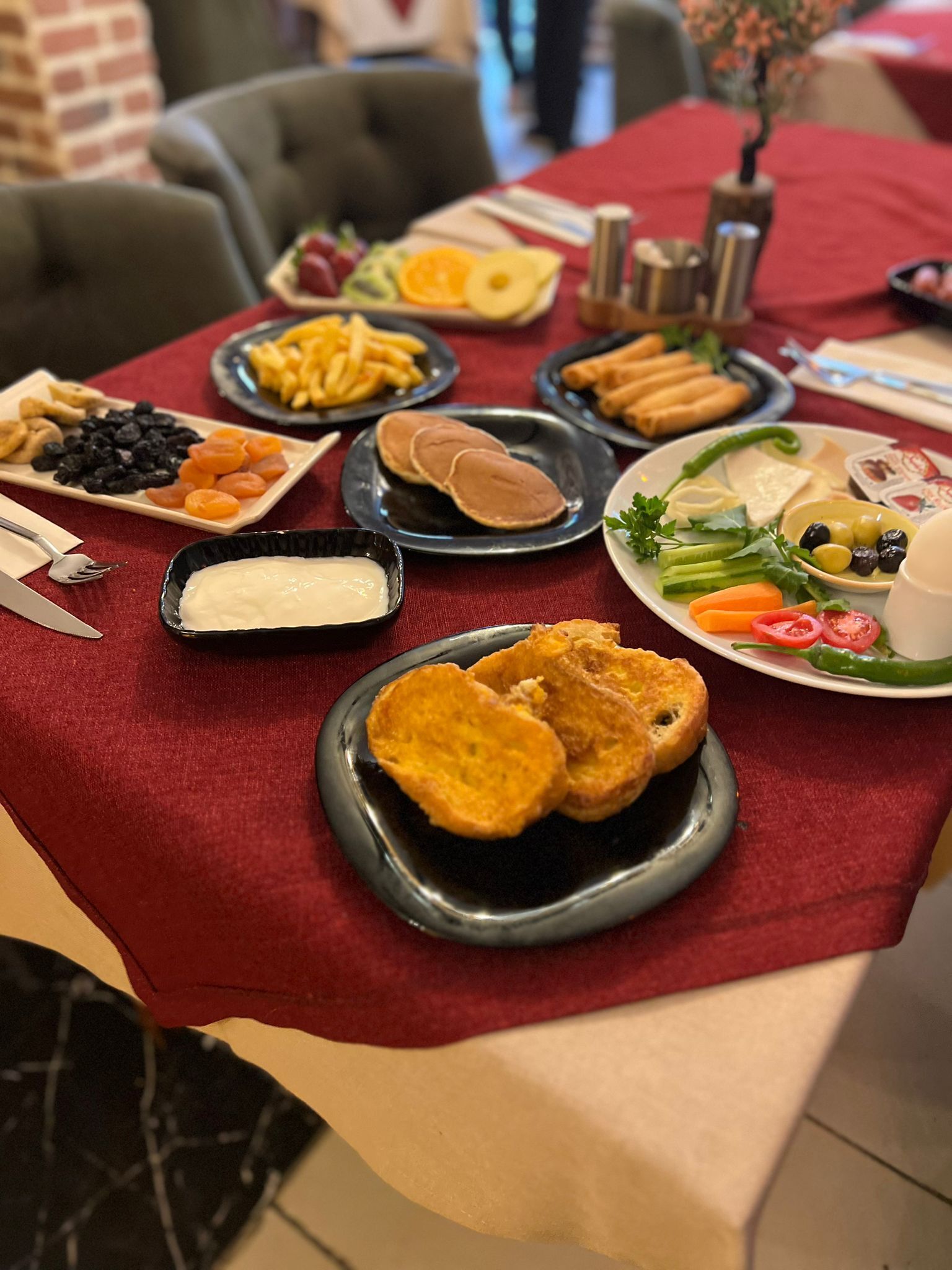 Une table où l’on trouve divers plats, notamment des aliments frits, des fruits et des légumes.