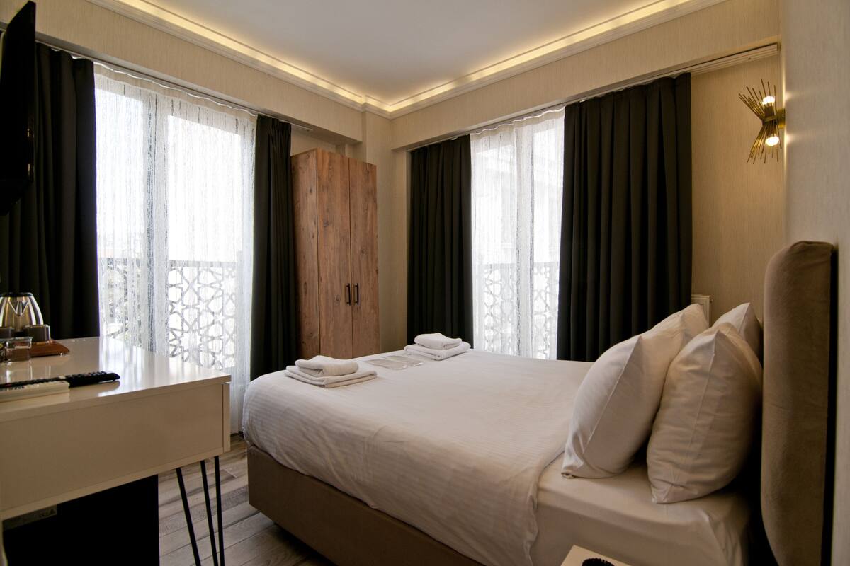A hotel room with a bed, a desk, and a wardrobe.