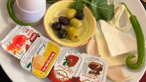 A plate with various food items including cheese, olives, tomatoes, and vegetables. - SULTAN SÜLEYMAN  APART HOTEL (Istanbul)