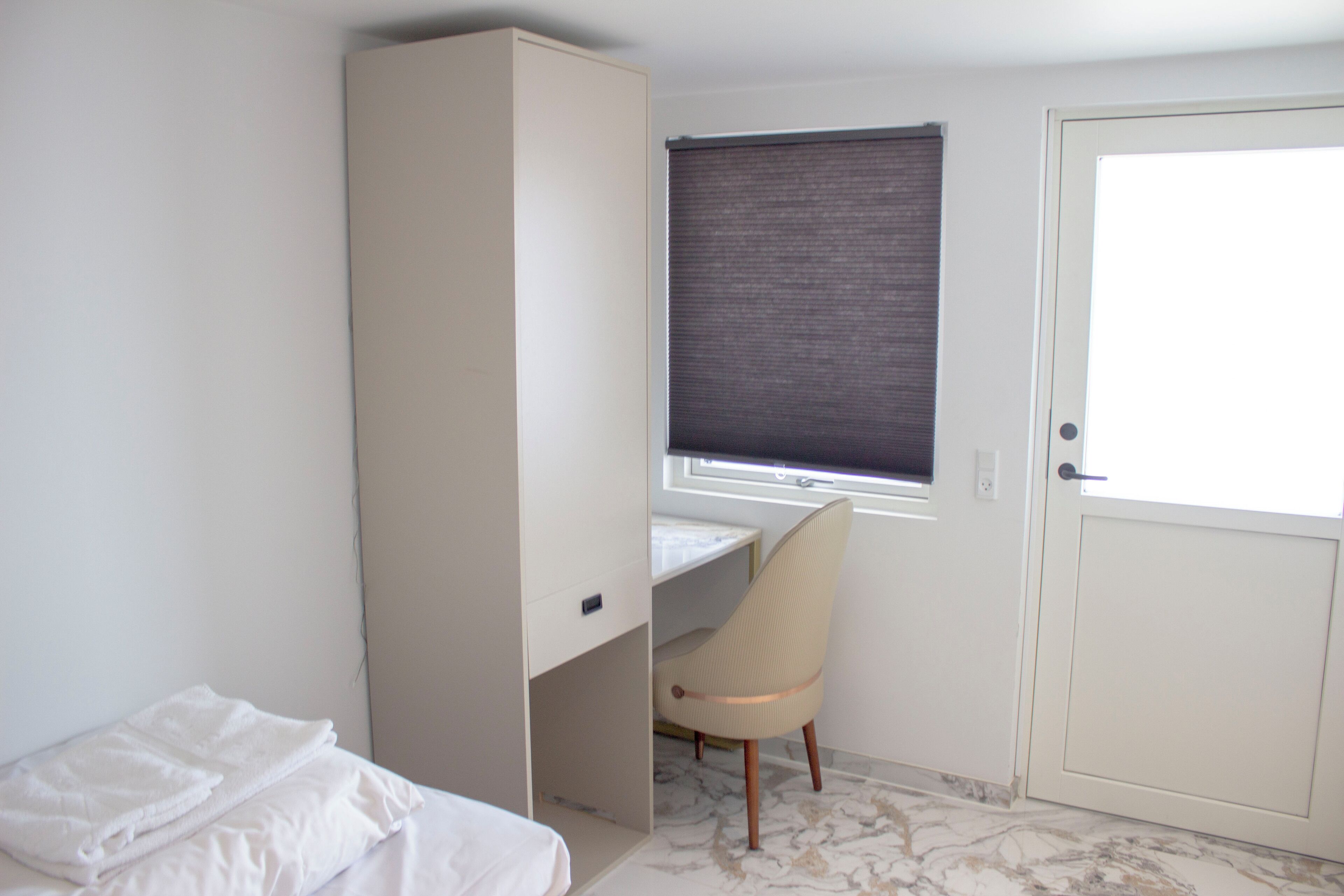 Un dormitorio con cama, escritorio, silla y armario.