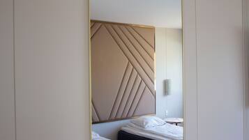 Una camera d'albergo moderna con una testiera geometrica, un comodino e un punto luce a parete.