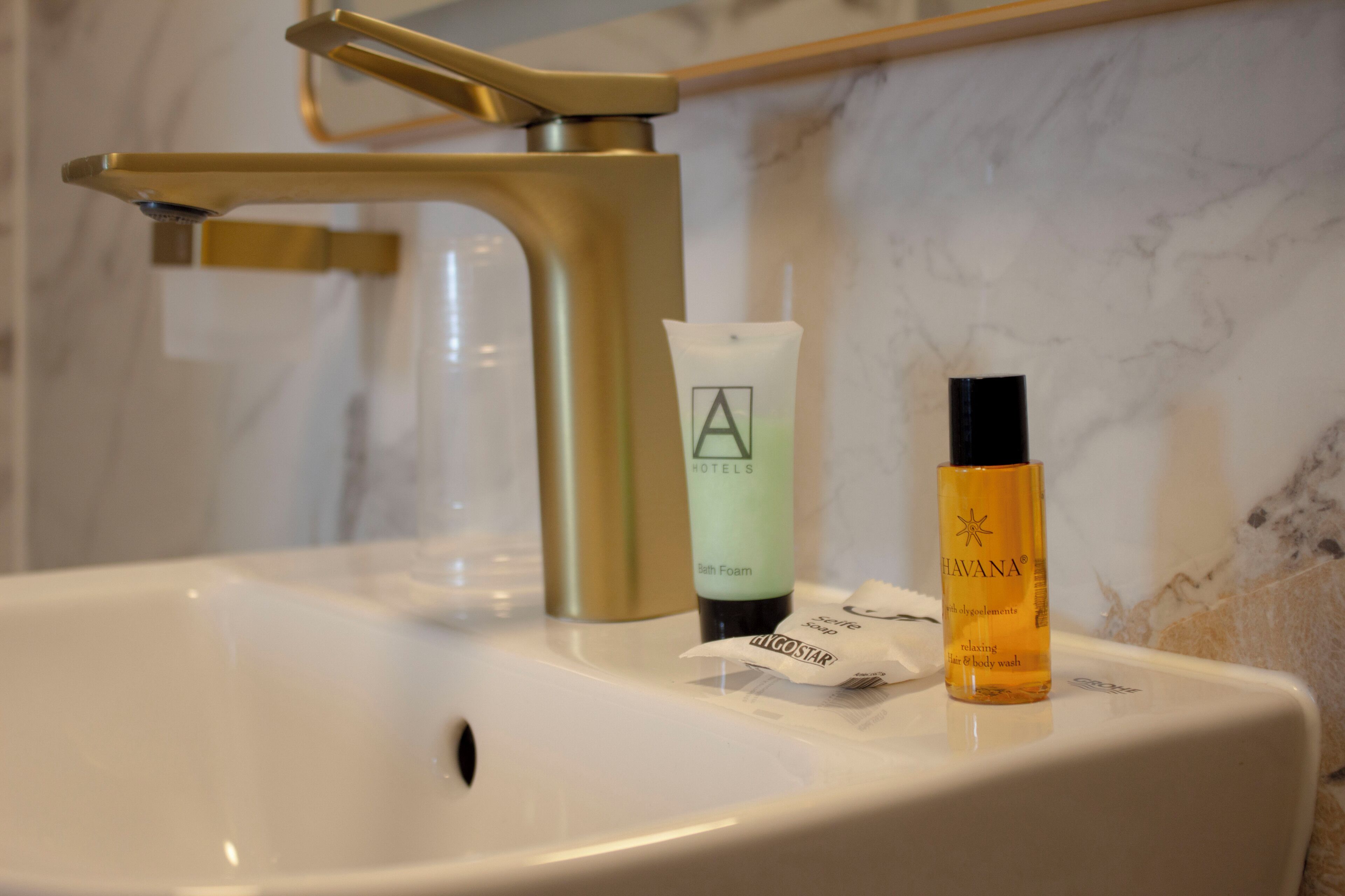 A bathroom sink with a gold faucet, a bath foam bottle, and a body wash bottle.