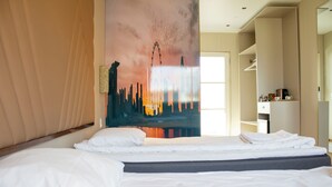 Habitación de hotel con una cama, un cuadro de un horizonte urbano y vista de la ciudad desde la ventana.
