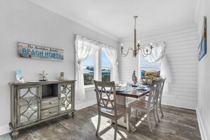 Uma área de refeições com uma mesa de madeira, cadeiras, um candelabro e um aviso na parede.