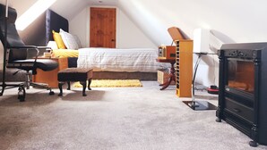 Un dormitorio con cama, escritorio, silla, chimenea y tragaluz.