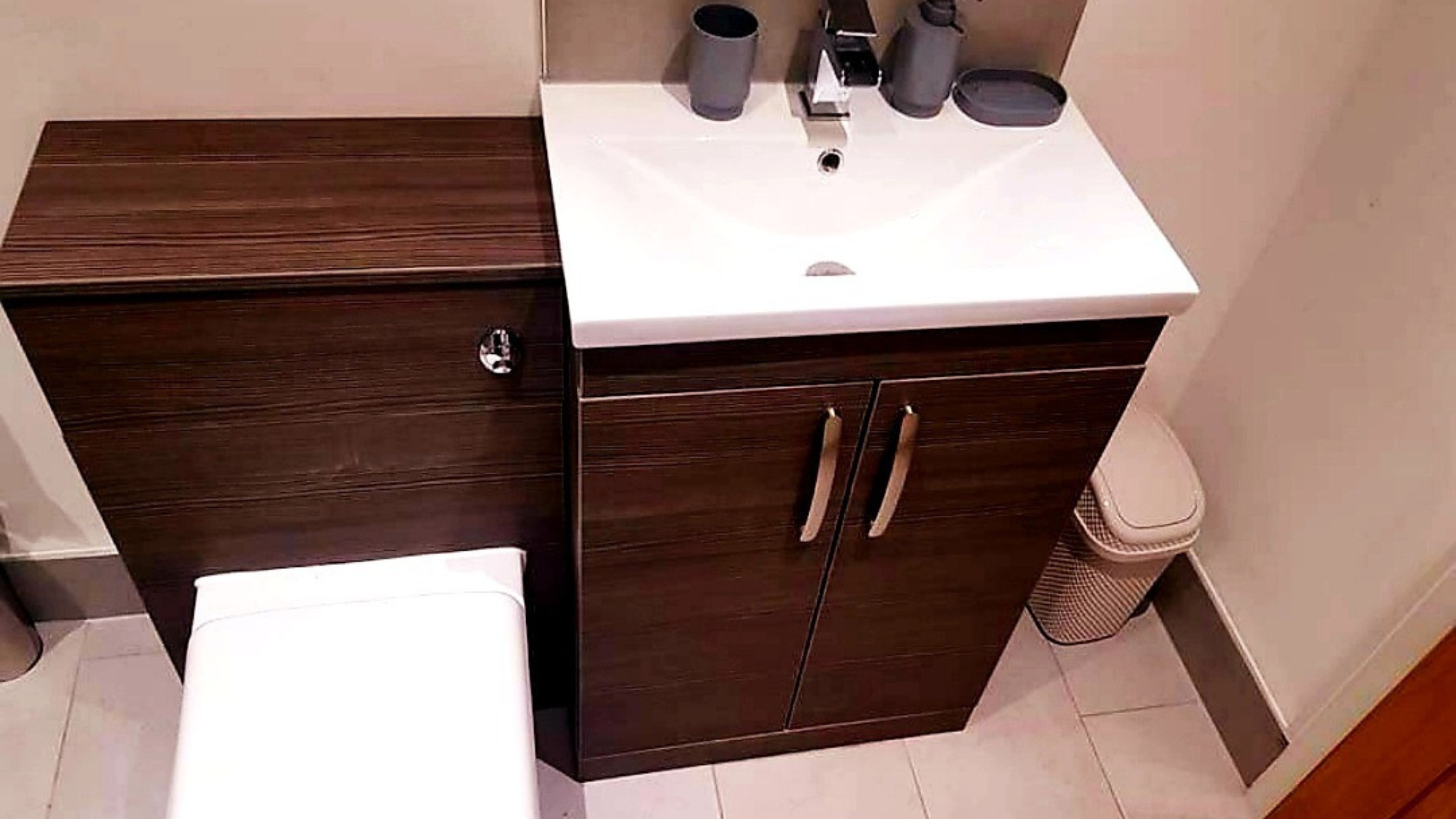 A bathroom with a dark wooden vanity, a white sink, and a toilet.