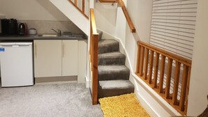 Una escalera con barandillas de madera que lleva a una cocina.