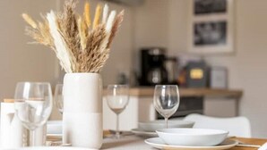 A dining table with a vase of dried pampas grass, a coffee machine, and a framed picture on the wall. - Maisonette, Wi-Fi, Parking, Fireplace (Erfurt)