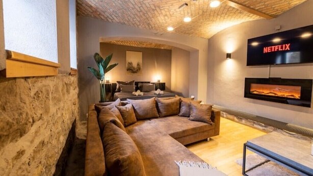A cozy living room with a large sectional sofa, a fireplace, and a mounted TV displaying the Netflix logo. - Maisonette, Wi-Fi, Parking, Fireplace (Erfurt)