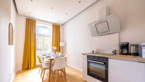 A modern kitchen with a built-in oven and a microwave, a dining area with a table and chairs, and a window with curtains. - Maisonette, Wi-Fi, Parking, Fireplace (Erfurt)