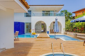 A modern house with a swimming pool, wooden deck, and outdoor seating area. - SA08 Casa 5 Suítes - Quintas do Sauípe (Mata de São João)