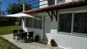A patio with a table and chairs, a white door, and a window. - Skiathos Modern Garden Escape Apt (Skiathos)