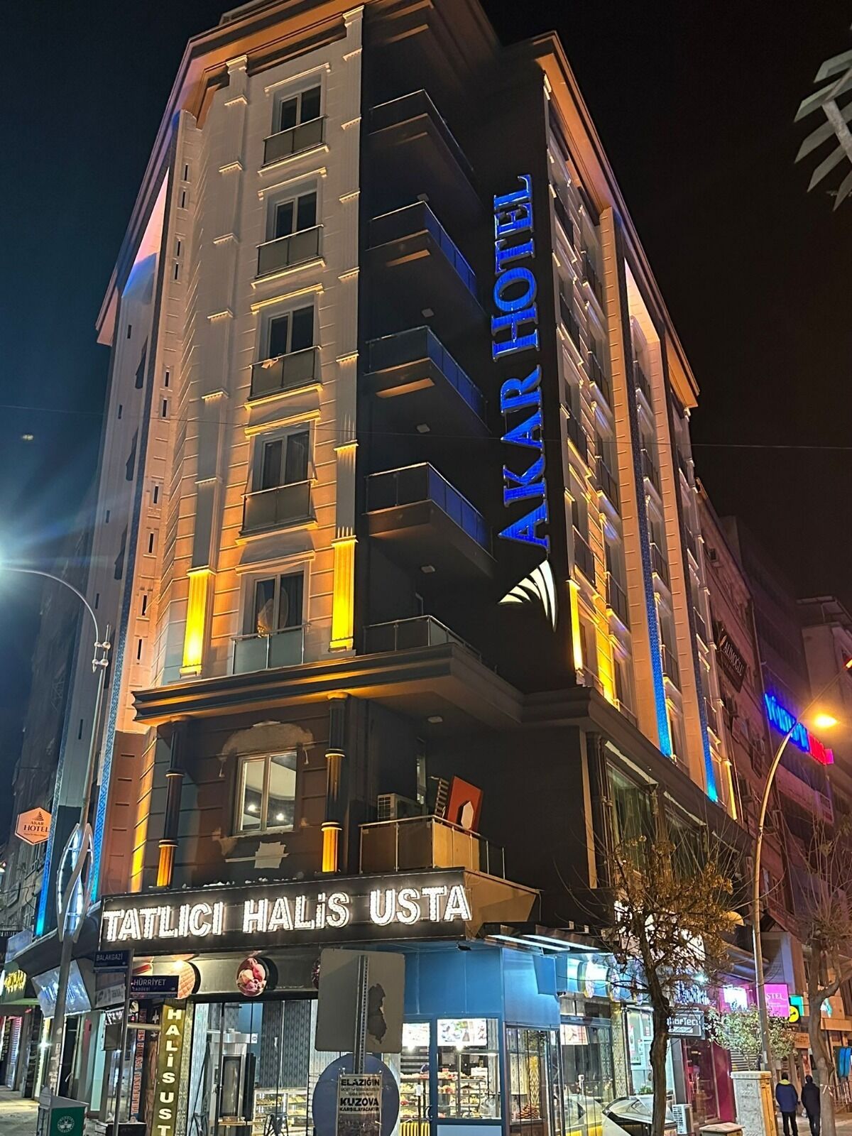 A hotel with a prominent sign reading "AKAR HOTEL" and a ground-level shop named "TATLICI HALIS USTA".
