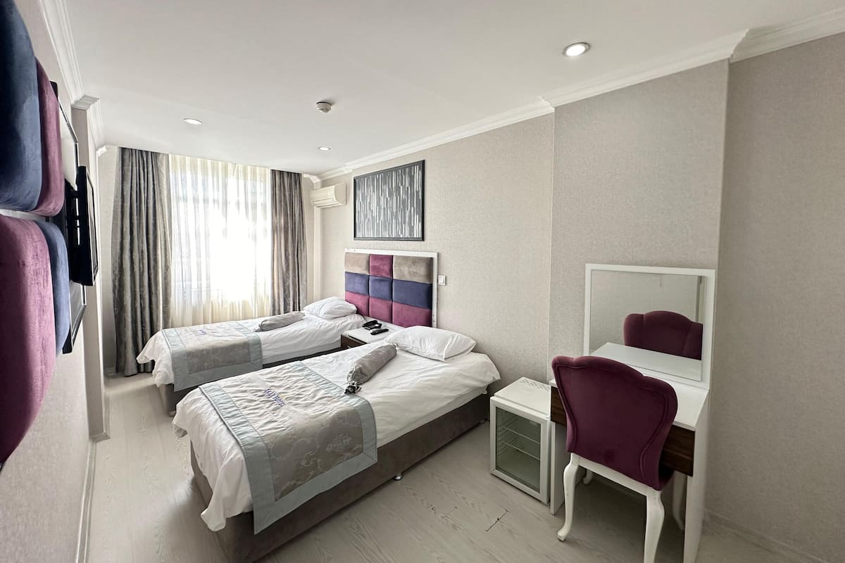 Una habitación de hotel con dos camas, un escritorio, una silla y un espejo grande.