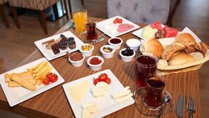 Et morgenbord med forskellige spiser, blandt andet brød, ost, tomater og drikkevarer.