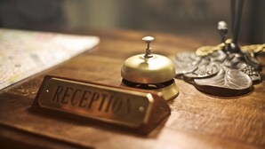 Et receptionsområde med en messingklokke, en navneskilte med teksten "RECEPTION" og en dekorativ metaldetalje.